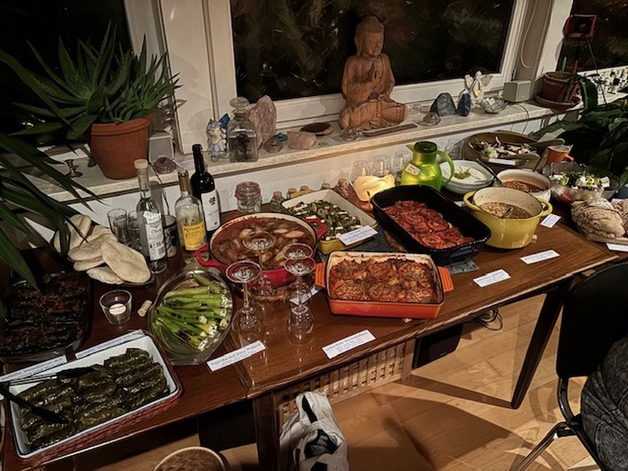 Gedeckter Buffettisch bei Kerzenlicht mit gefüllten Weinblättern, Fladenbrot und griechischen Speisen