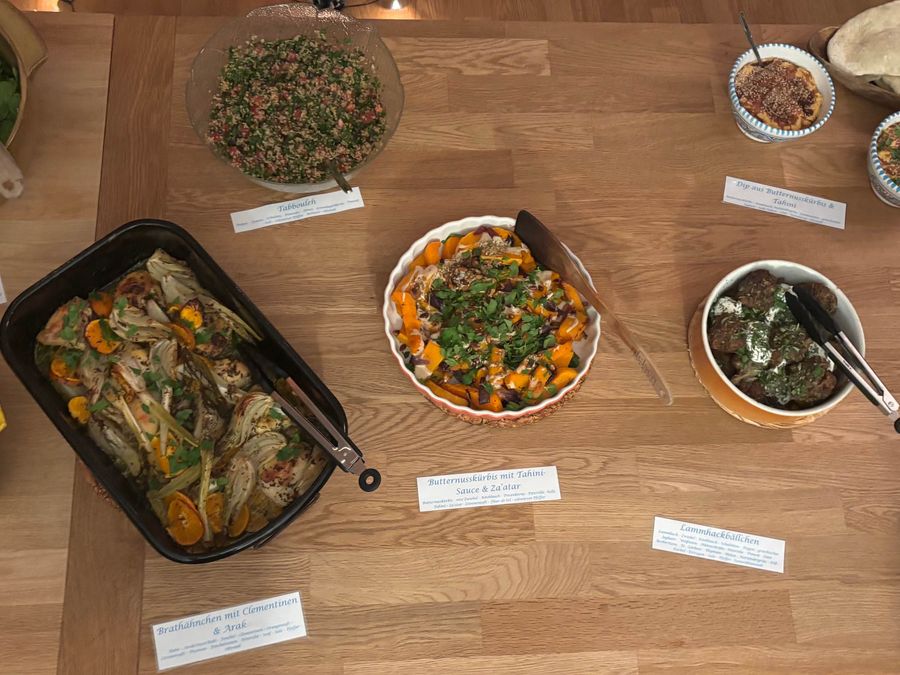 Buffet mit gefülltem Gemüse, Salaten und Fladenbrot, jede Schale mit einem beschrifteten Kärtchen